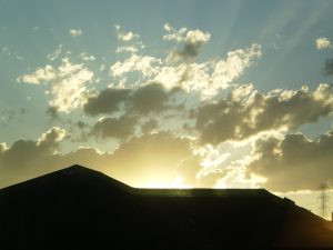 image of the sun shining over a rooftop in silhouette 